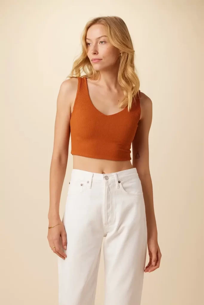 Woman wearing an orange Amour Vert tank top and white trousers, made in the usa