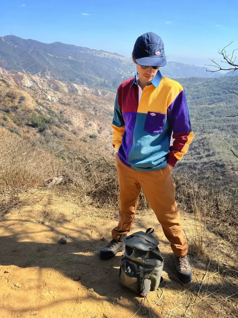 Man wearing an outfit including a made in USA hat, top, and trousers